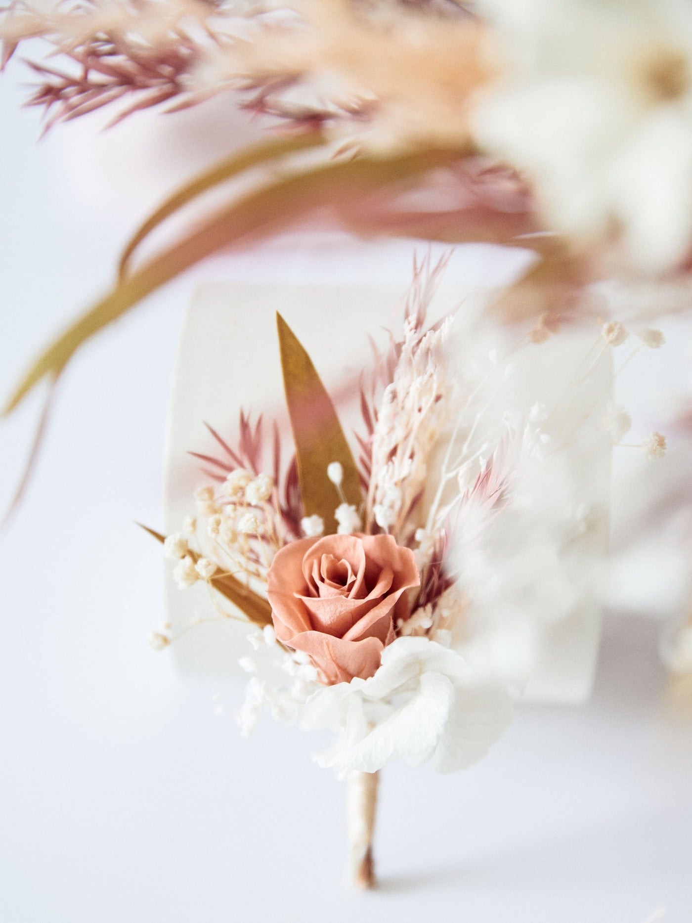 the boutonniere is leaning on a white stand on a white background