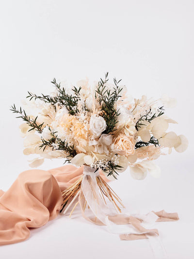 the wedding bouquet is standing on white background near peach fabric