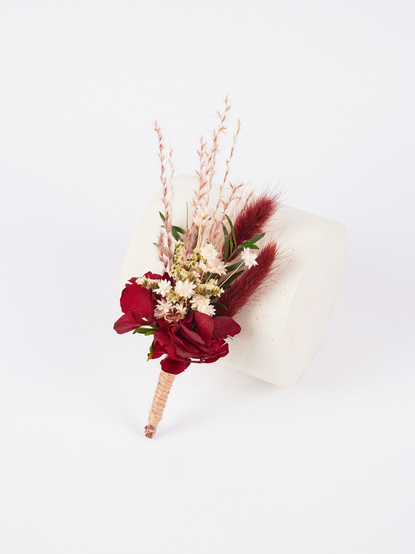 the boutonniere is leaning on a white stand on a white background