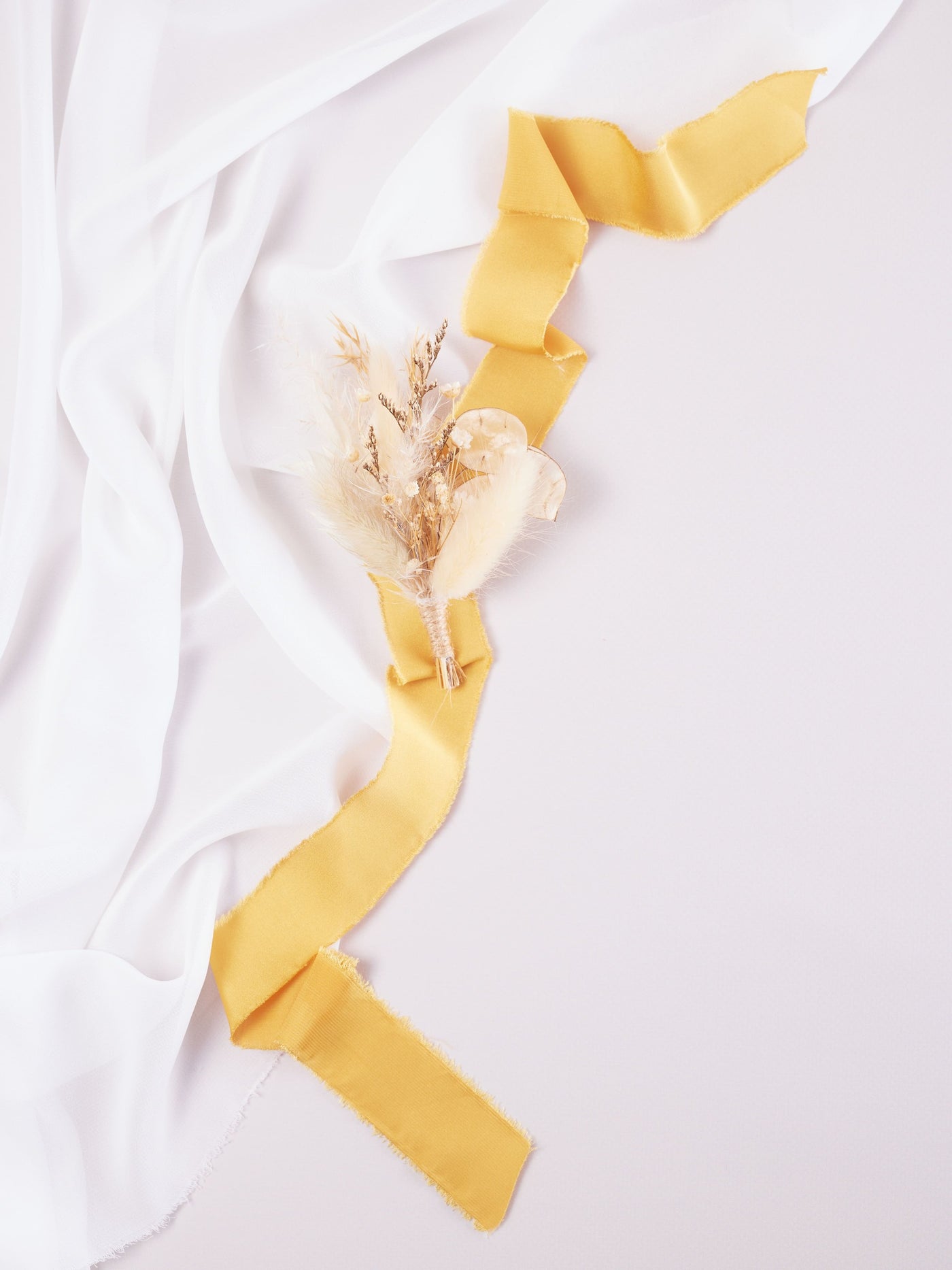 wedding boutonniere on cream ribbon and white organza on white background