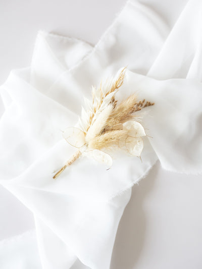 wedding boutonniere is lying on white organza