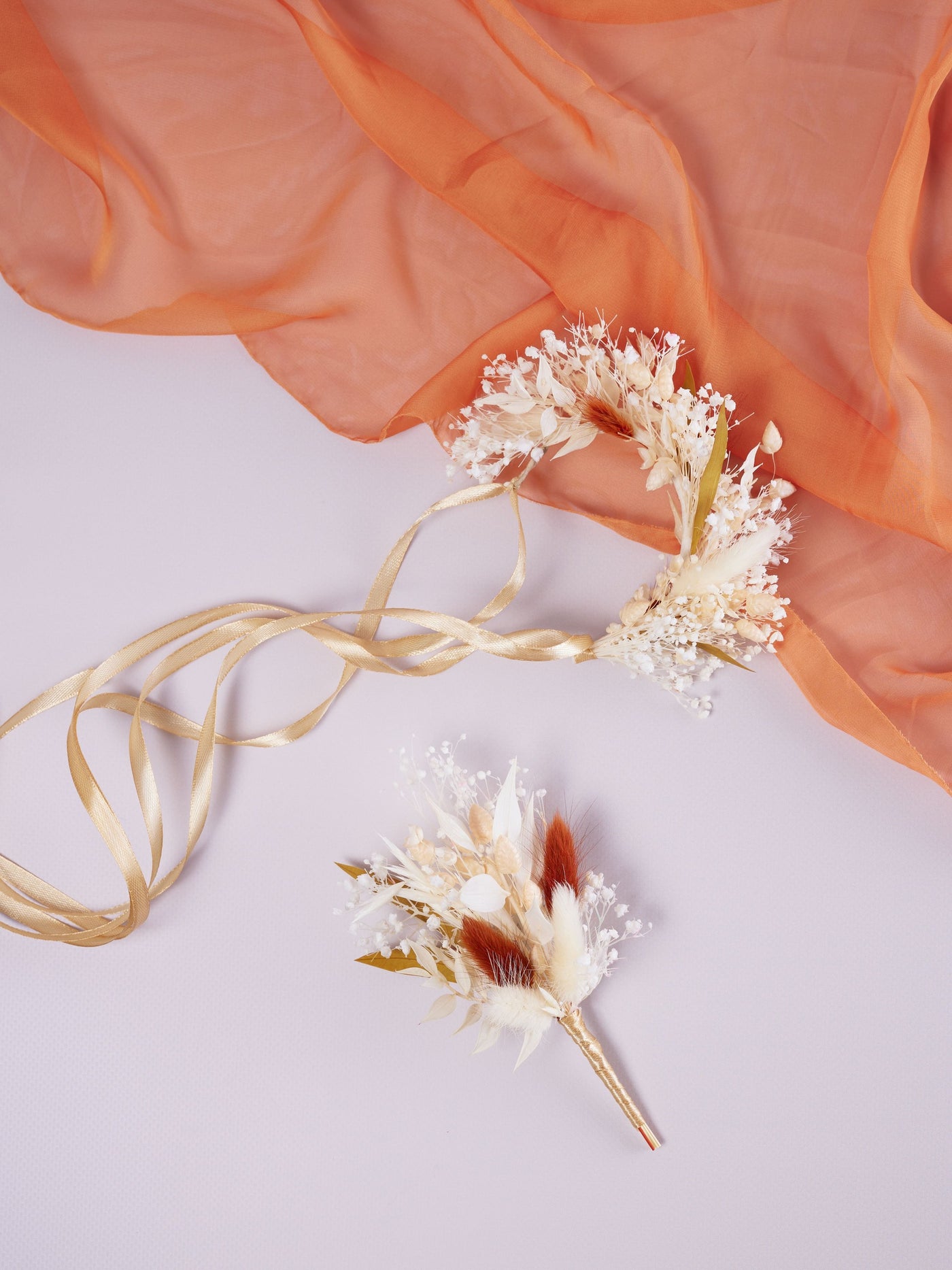 corsage is lying near boutonniere on orange organza and white background