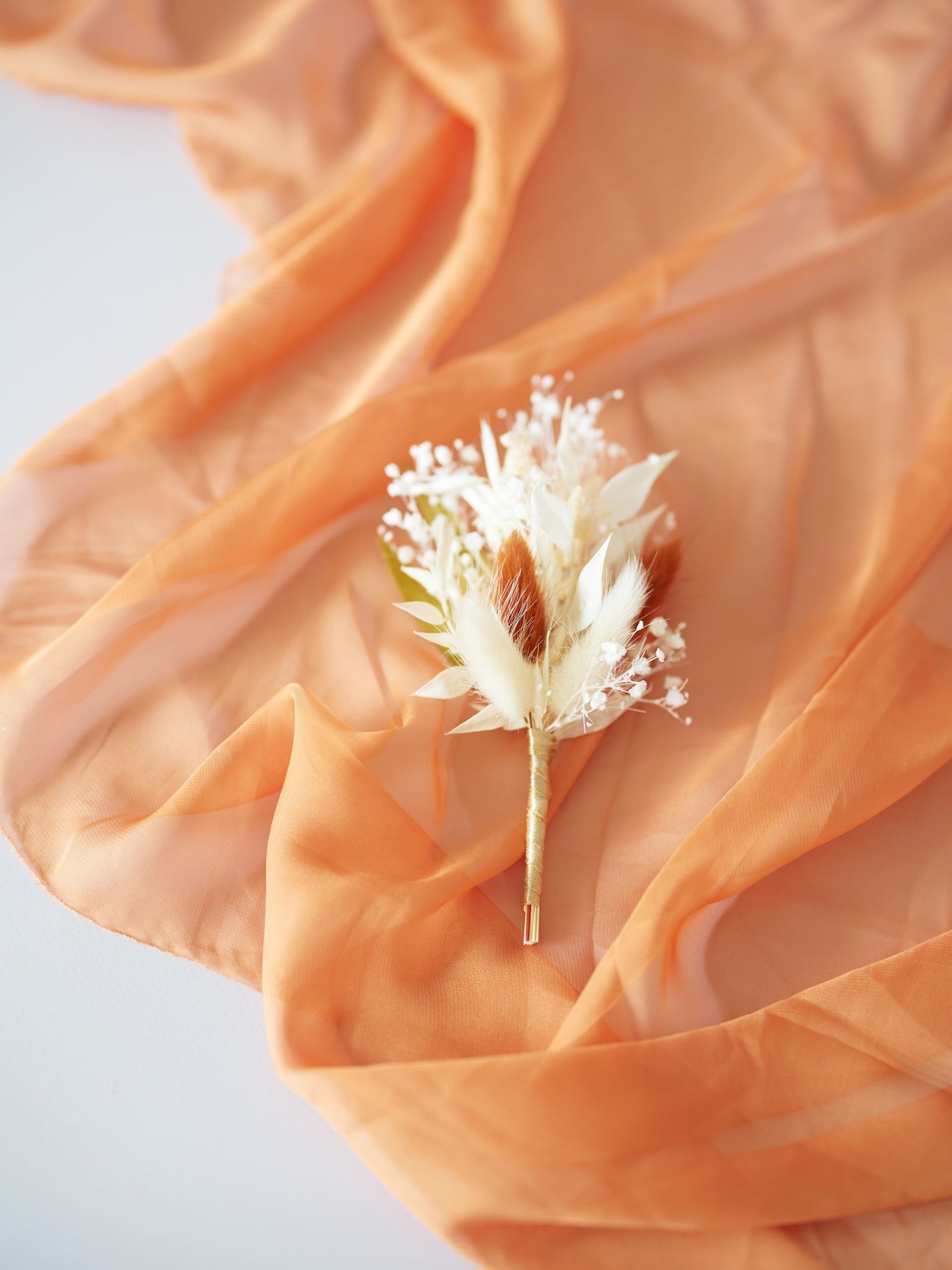 boutonniere on white background on terracotta organza cloth