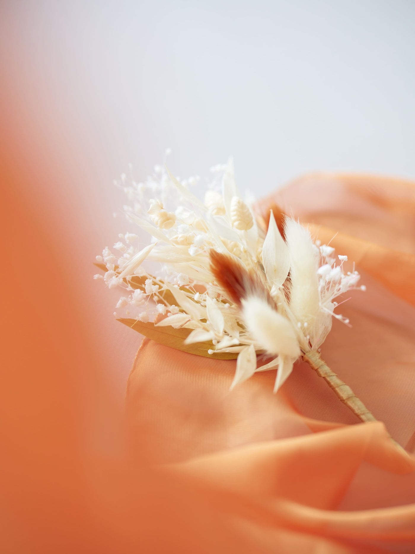 boutommiere is lying on orange organza and white background 5