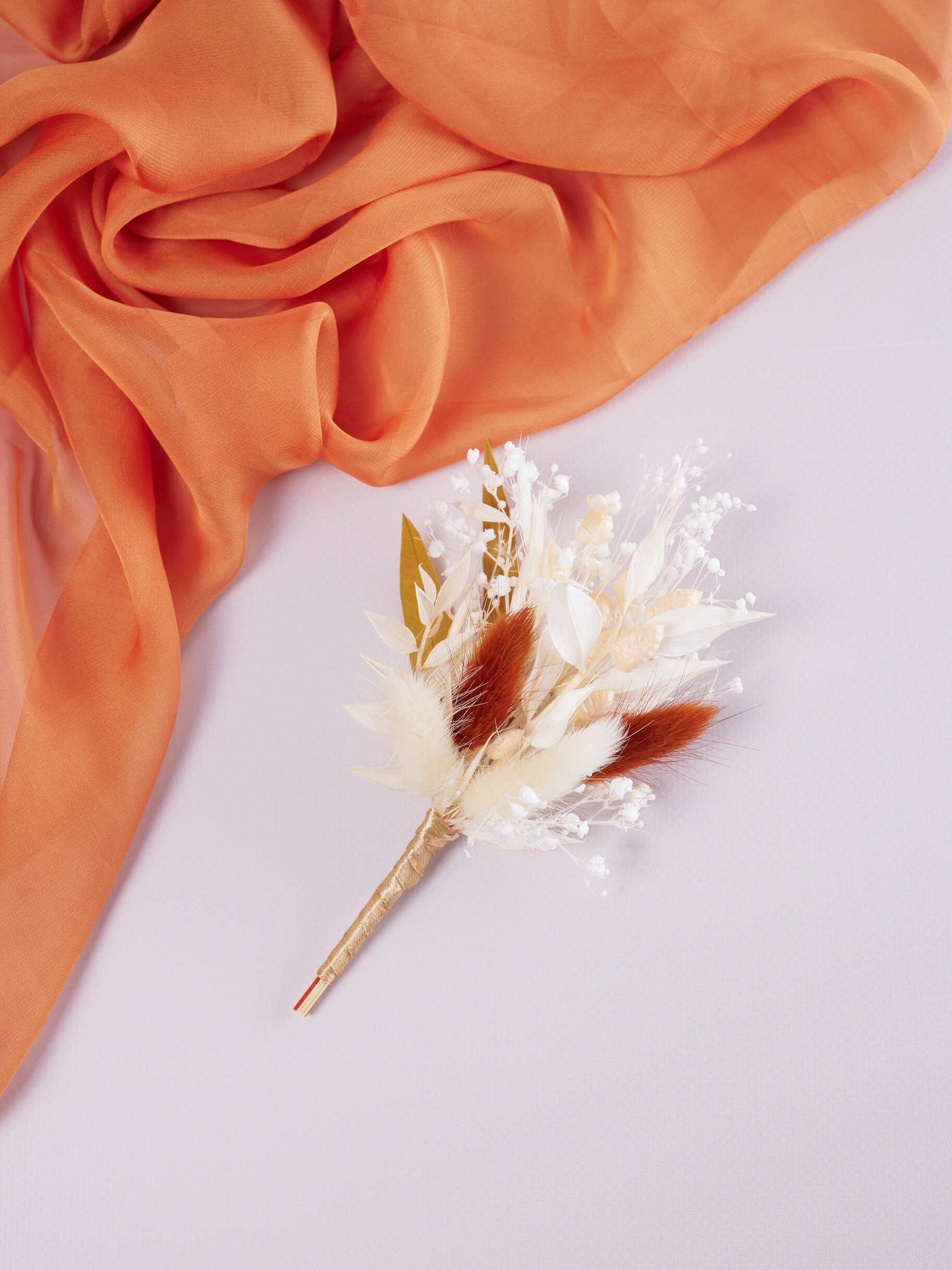 boutonniere on white background near terracotta organza cloth