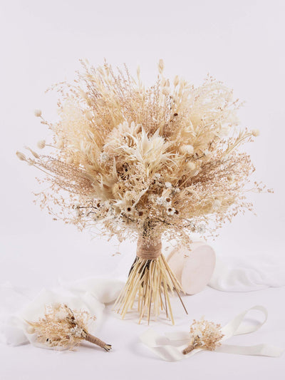 corsage is lying on white background near wedding bouquet and boutonniere on white fabric