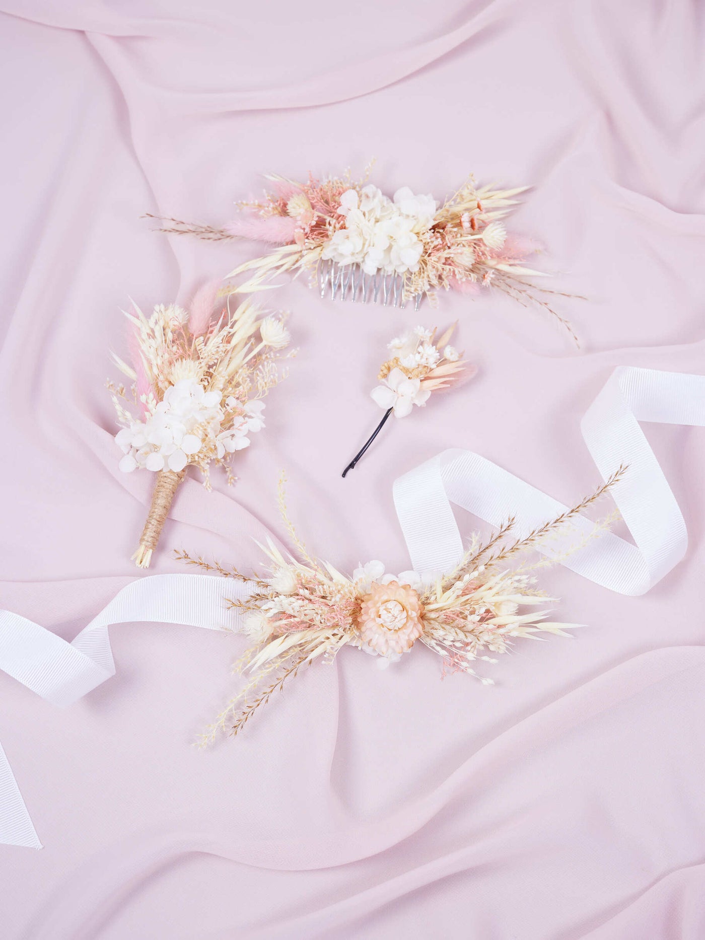 corsage, wedding comb, bobby pin and boutonniere lies on pink organza