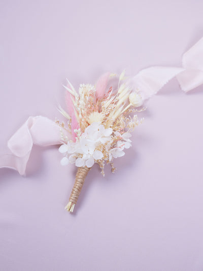 boutonniere lying on pink organza and white ribbon