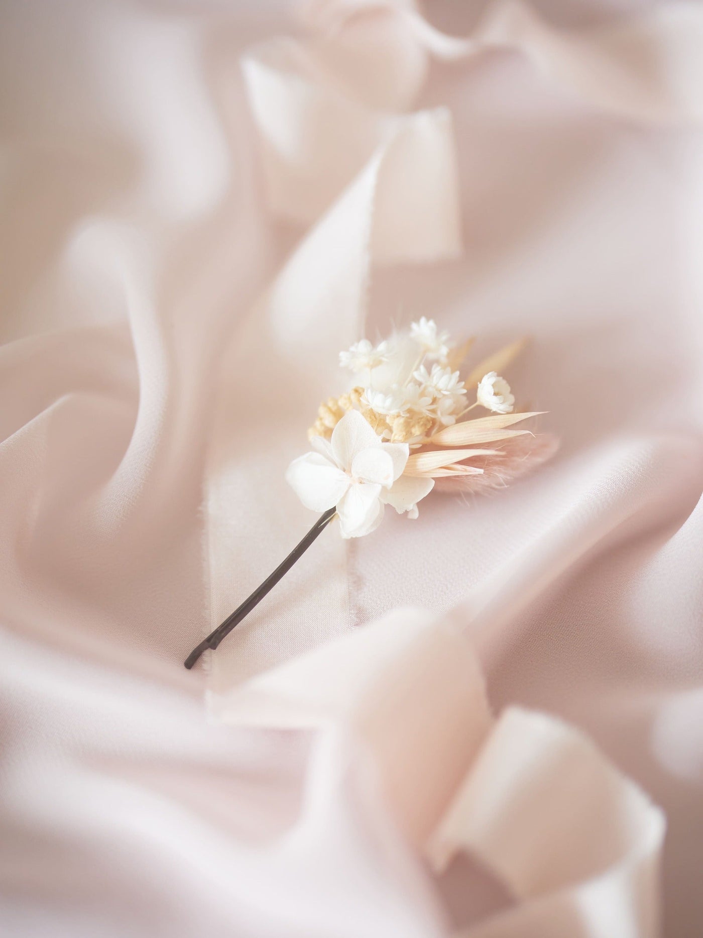 bobby pin is lying on white ribbon and white silk fabric