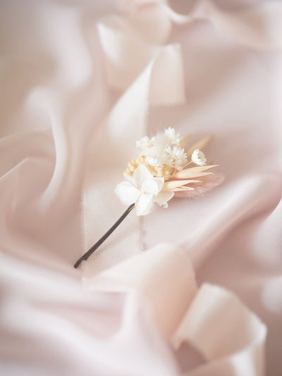 bobby pin is lying on white ribbon and white silk fabric