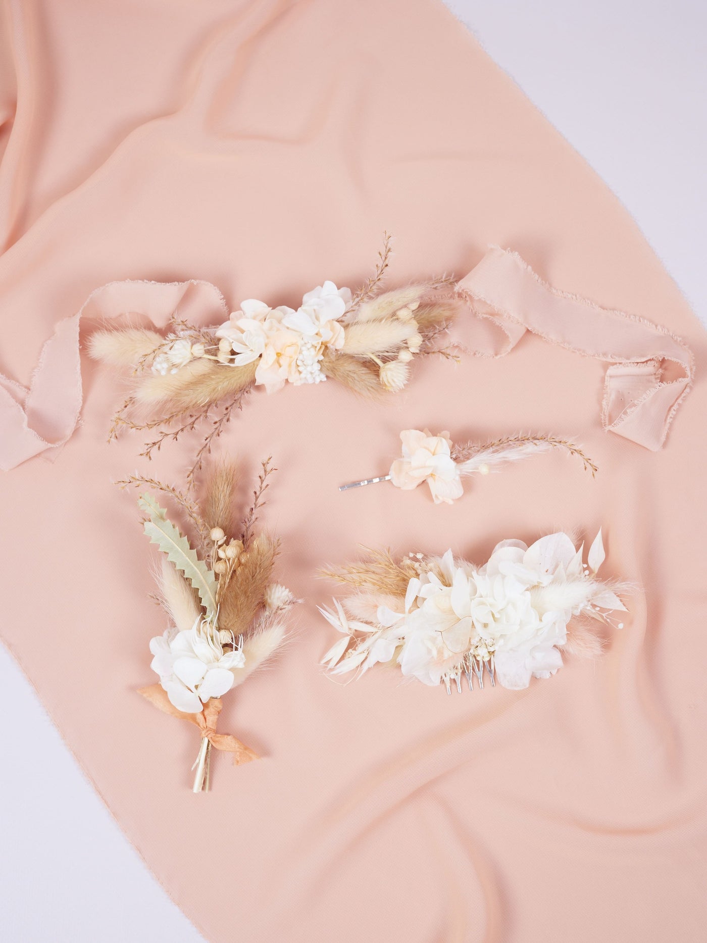 bobby pin is lying near wedding comb, boutonniere, corsage on pink silk and white background