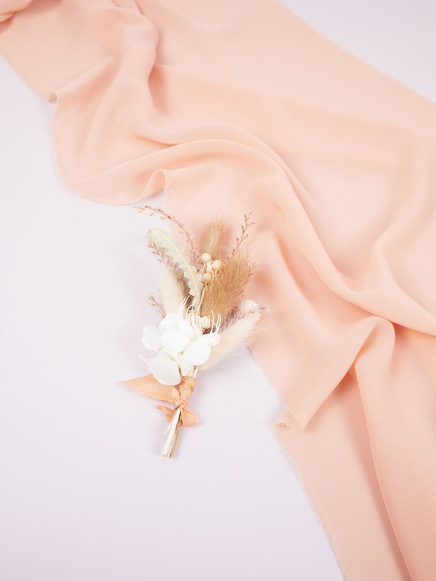 boutonniere is lying on white background and pink organza