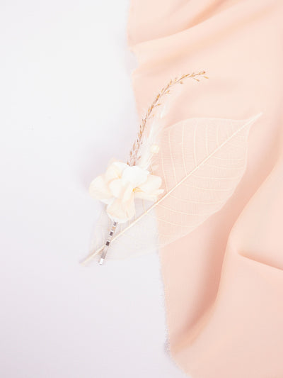 bobby pin is lying on white background near pink organza